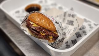 Freshly cooked smash burger with two patties wrapped in paper and ready to eat