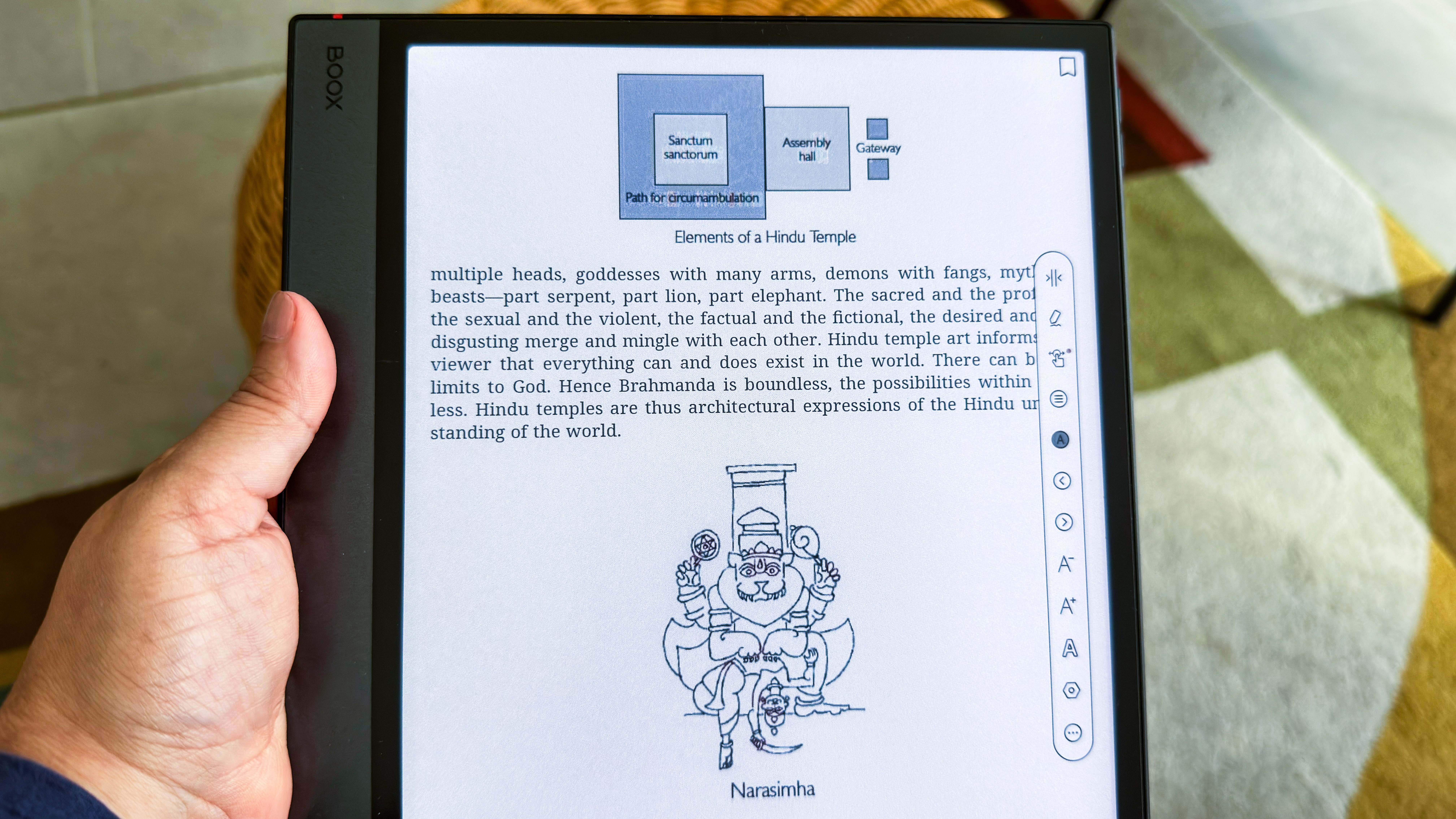 A hand holding the Boox Note Air5 C showing a page of a book with words and diagrams