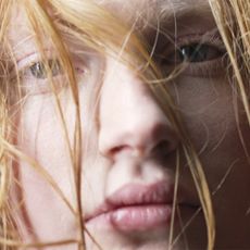 A close up shot of a model with hair blowing over her face