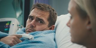 Iain Dean lying in a hospital bed. 
