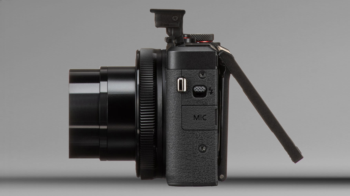 Side view of a black digital camera with lens extended and flip-out LCD screen opened