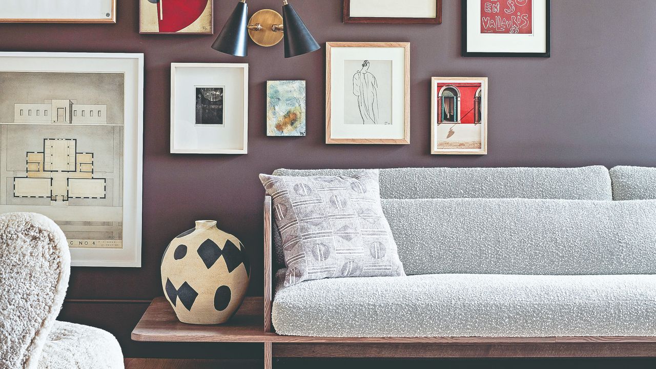 A purple-painted living room with a gallery wall display and a mid century modern sofa in front