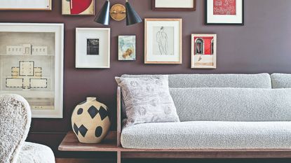 A purple-painted living room with a gallery wall display and a mid century modern sofa in front