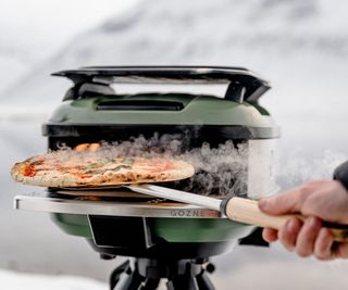 A Gozney Tread making a pizza on an icy lake