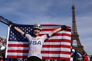 TOPSHOT US Kristen Faulkner celebrates her victory with a US flag in front of the Eiffel Tower after winning the womens cycling road race during the Paris 2024 Olympic Games in Paris on August 4 2024 Photo by David GRAY AFP Photo by DAVID GRAYAFP via Getty Images