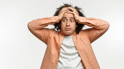 An anxious man holds his head.