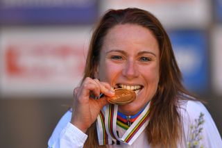 Annemiek van Vleuten bites her gold medal and shows off her new rainbow stripes