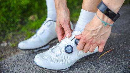 Image shows a rider putting on a pair of the best cycling shoes.