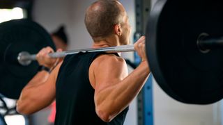 Rear view of man holding a barbell across his shoulders