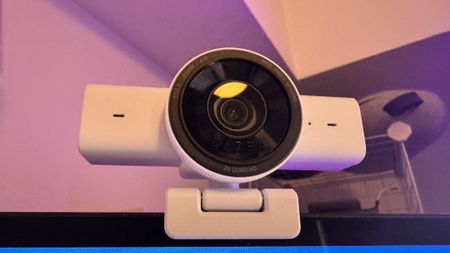 The Razer Kiyo V2 X webcam on a monior with red and purple light behind it