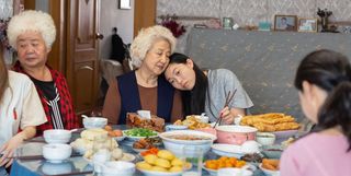 a family sits around a table while a girl leans her head on her grandmother's shoulder in The Farewell (2019)