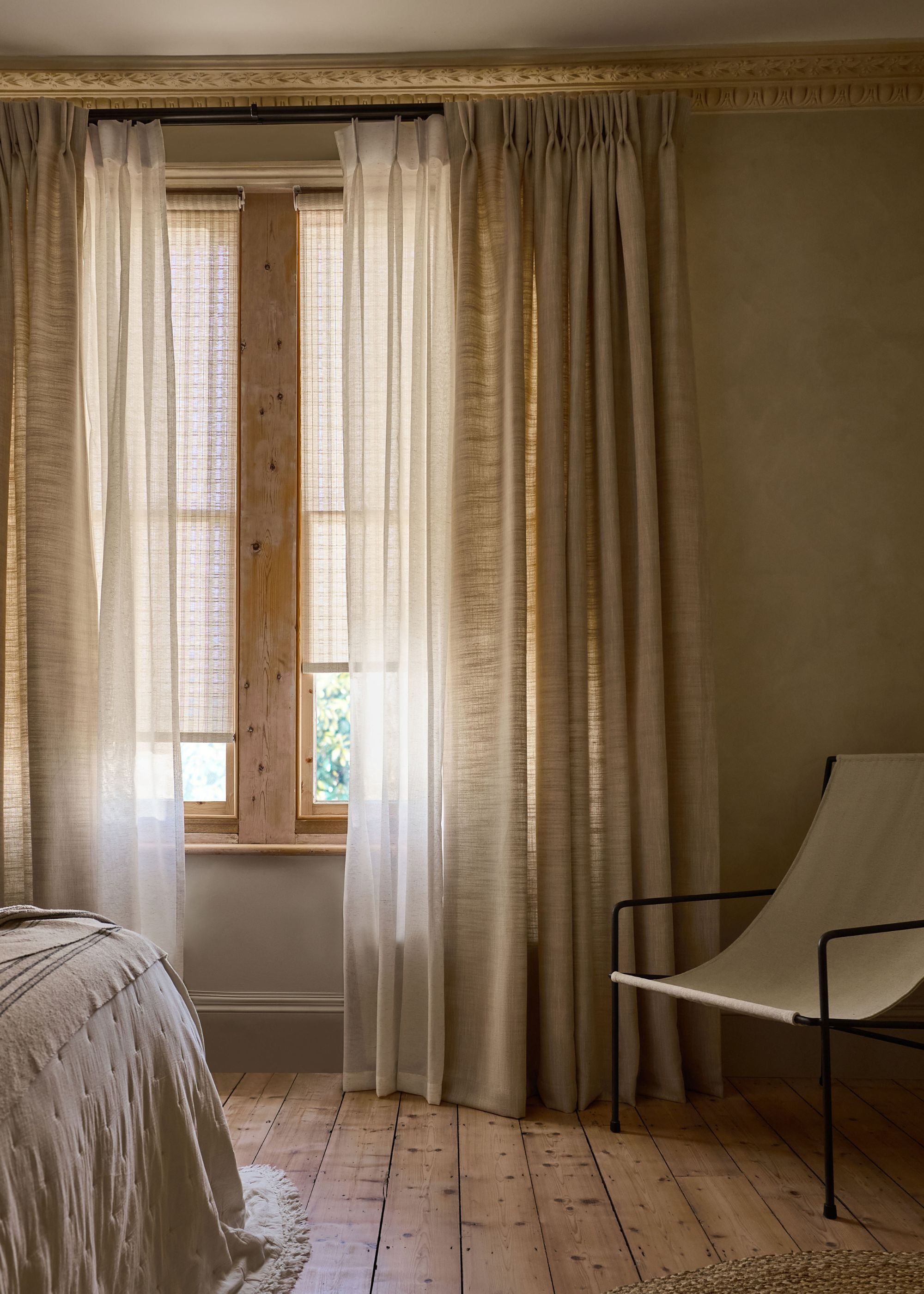 neutral bedroom with layered sheer and neutral pinch pleat curtains