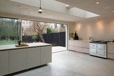 a minimalist plaster kitchen with wood cabinets, a concrete floor and a white aga