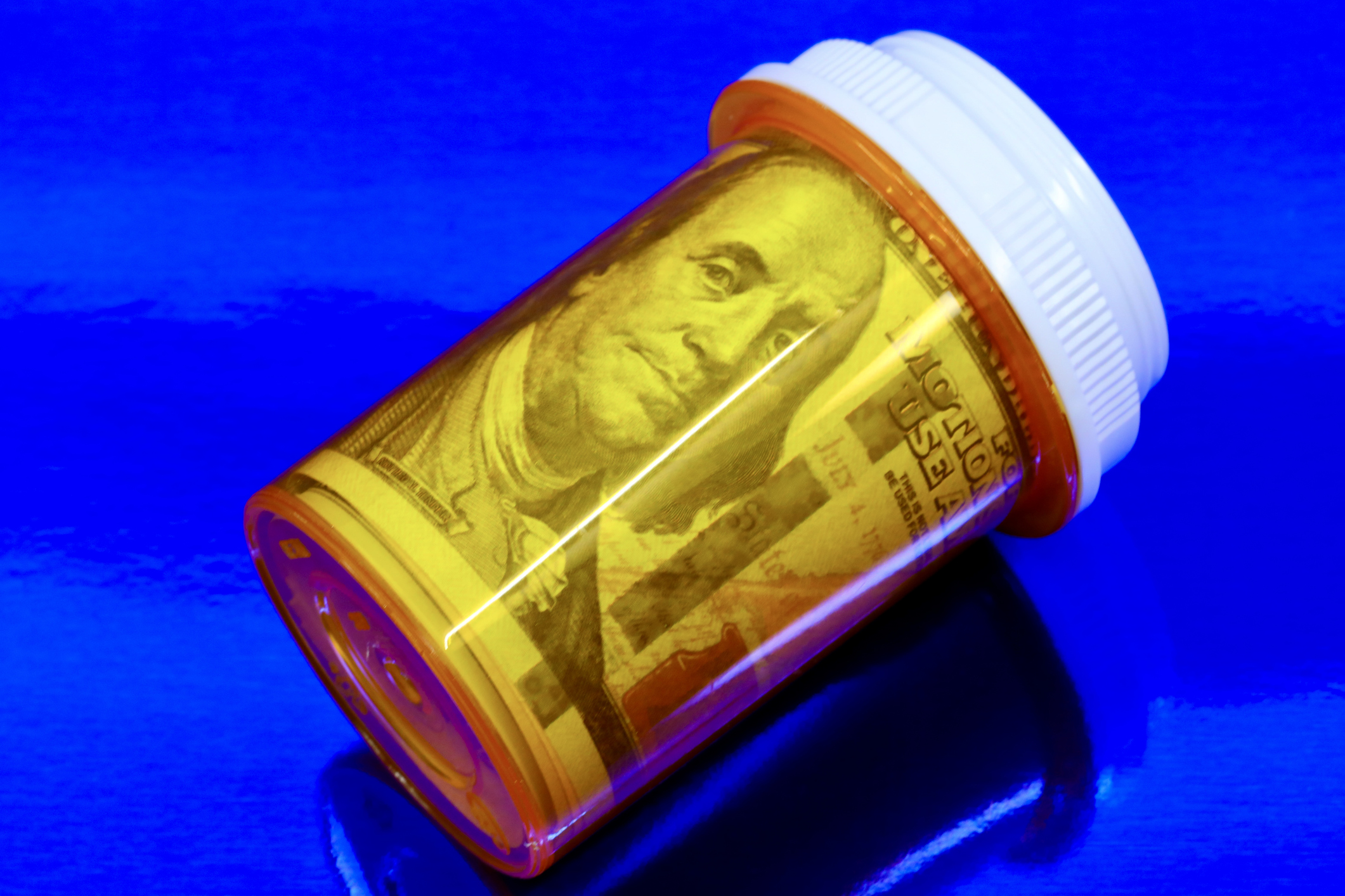 Conceptual image of medication being expensive - pill bottle and money