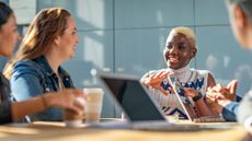 Women in tech sitting around a conference table with laptops.