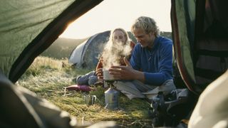 how to keep your tent clean while camping: couple cooking outside a tent