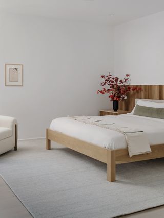 A bedroom with plain white walls and a single small piece of art