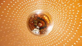 A gold-tinted disco ball reflecting light onto a gold ceiling