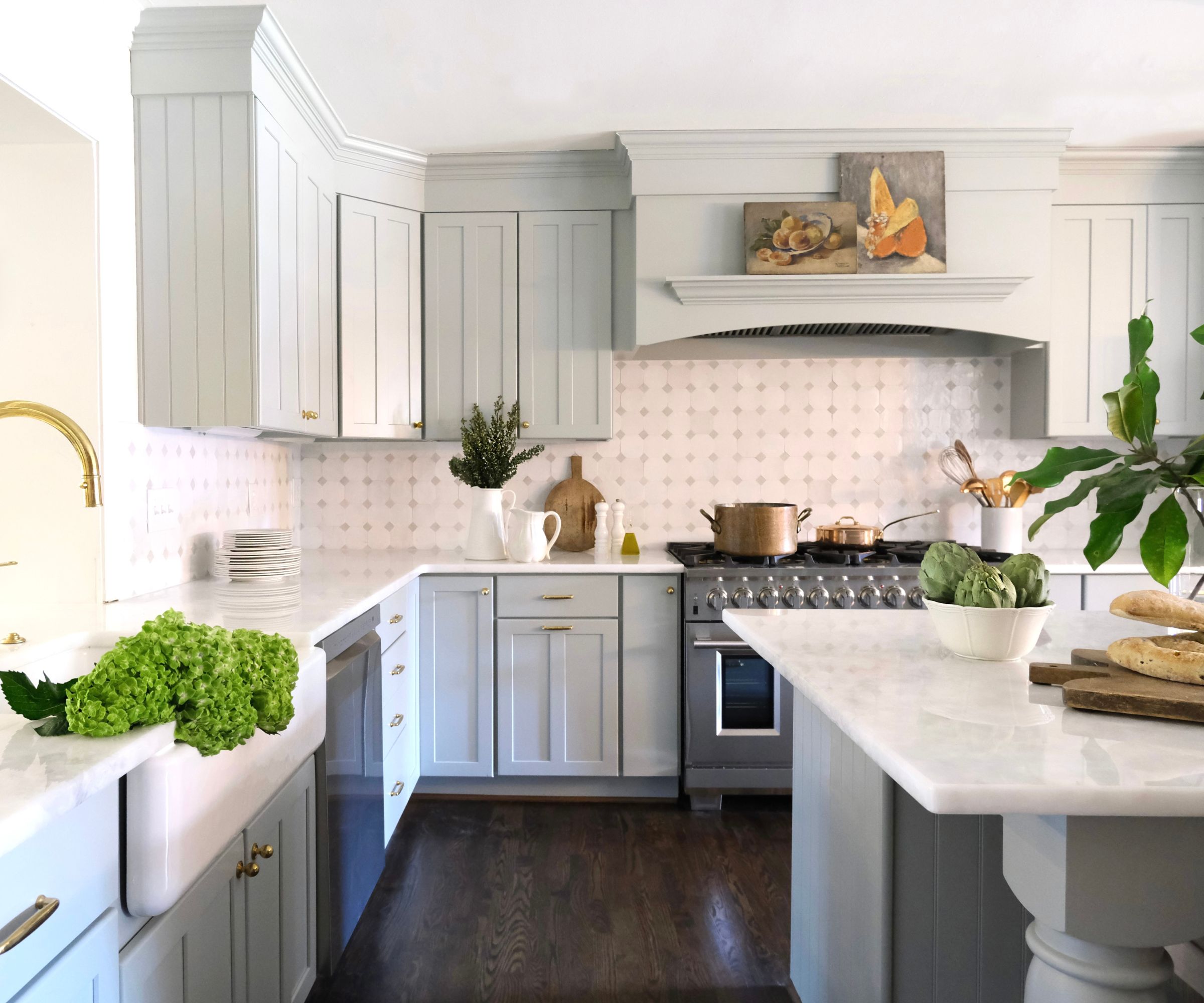 Kitchen with pale blue cabinets, marble island, tiled backsplash and ceramic white sink