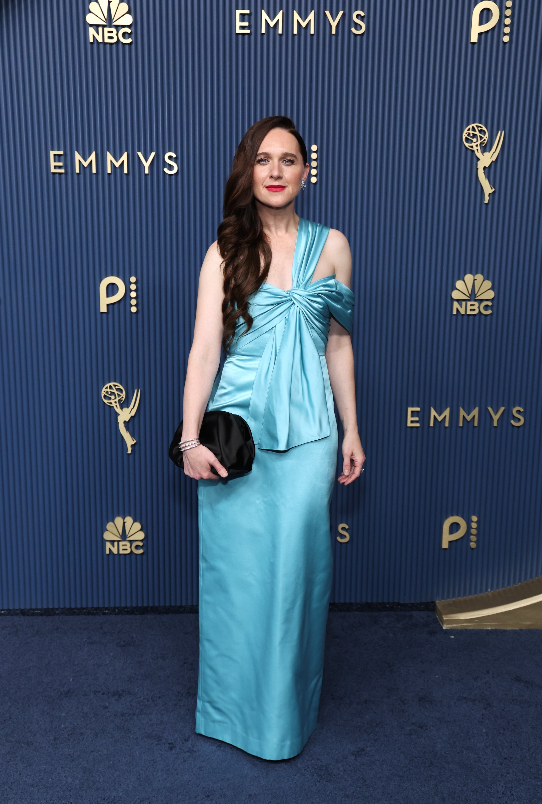 a woman with dark brown hair in a blue dress on an emmys blue step and repeat