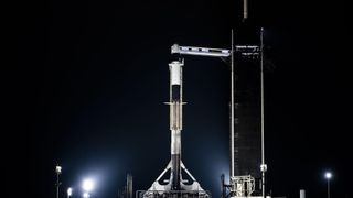 a black and white spacex falcon 9 rocket sits on a launch pad at night.