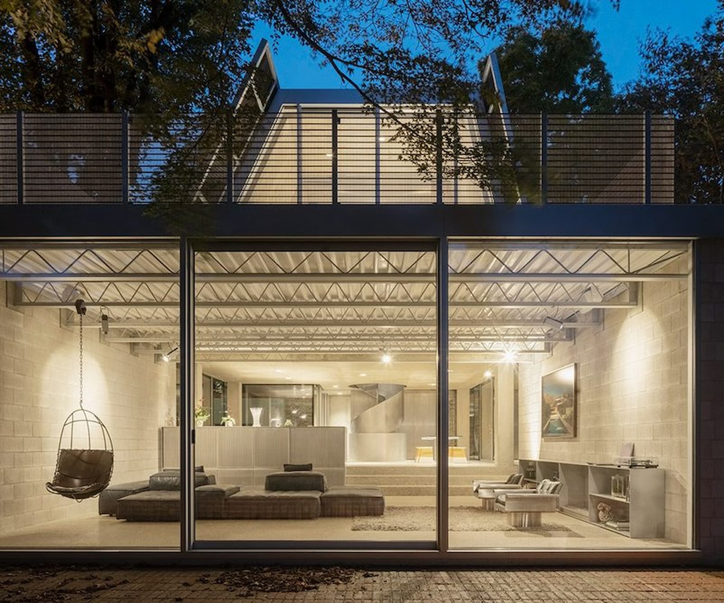 A bottom floor living room lit at night and seen through a floor-to-ceiling window