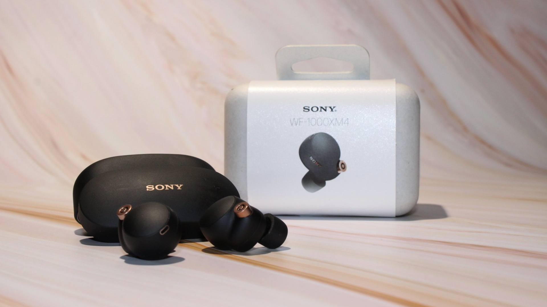 The Sony WF-1000XM4 outside the case, with the packaging