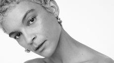 A black and white image of a model with short hair and earrings 