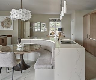 neutral coloured kitchen island with curved banquette seating built on to the back