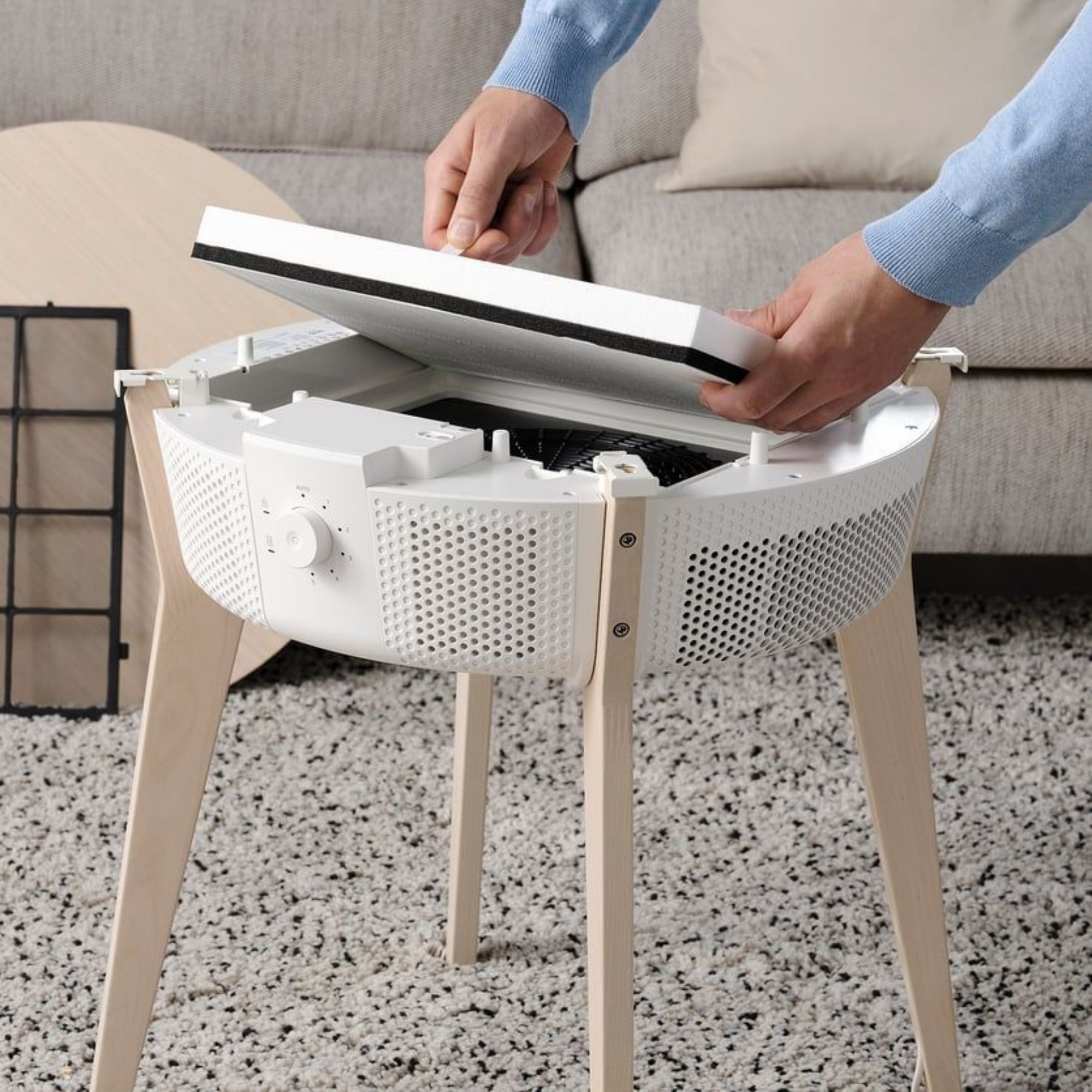 Hands inserting the filter into a white STARKVIND Table with Air Purifier