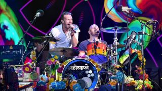 Chris Martin performing on stage with his band at Glastonbury 2016