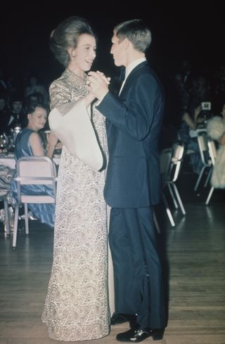 Princess Anne wearing a long brocade dress dancing with a man at a 1971 event