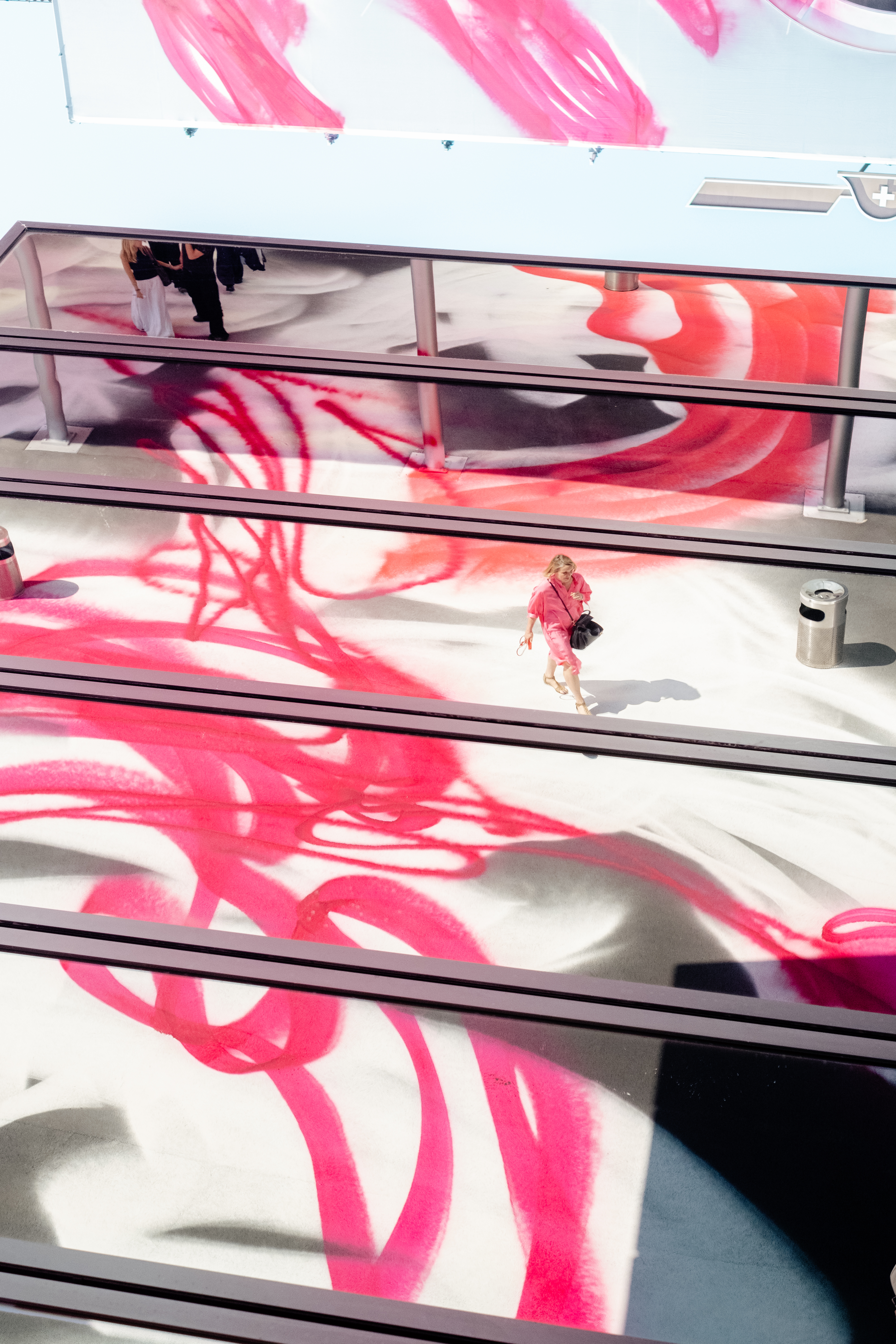 A series of lifestyle images depict people at leisure and play in a Swiss town bathing in sunshine, whether enjoying the weather near the river bank or abstract painting murals at an art fair.