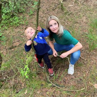 Woman standing next to boy playing with tree branch