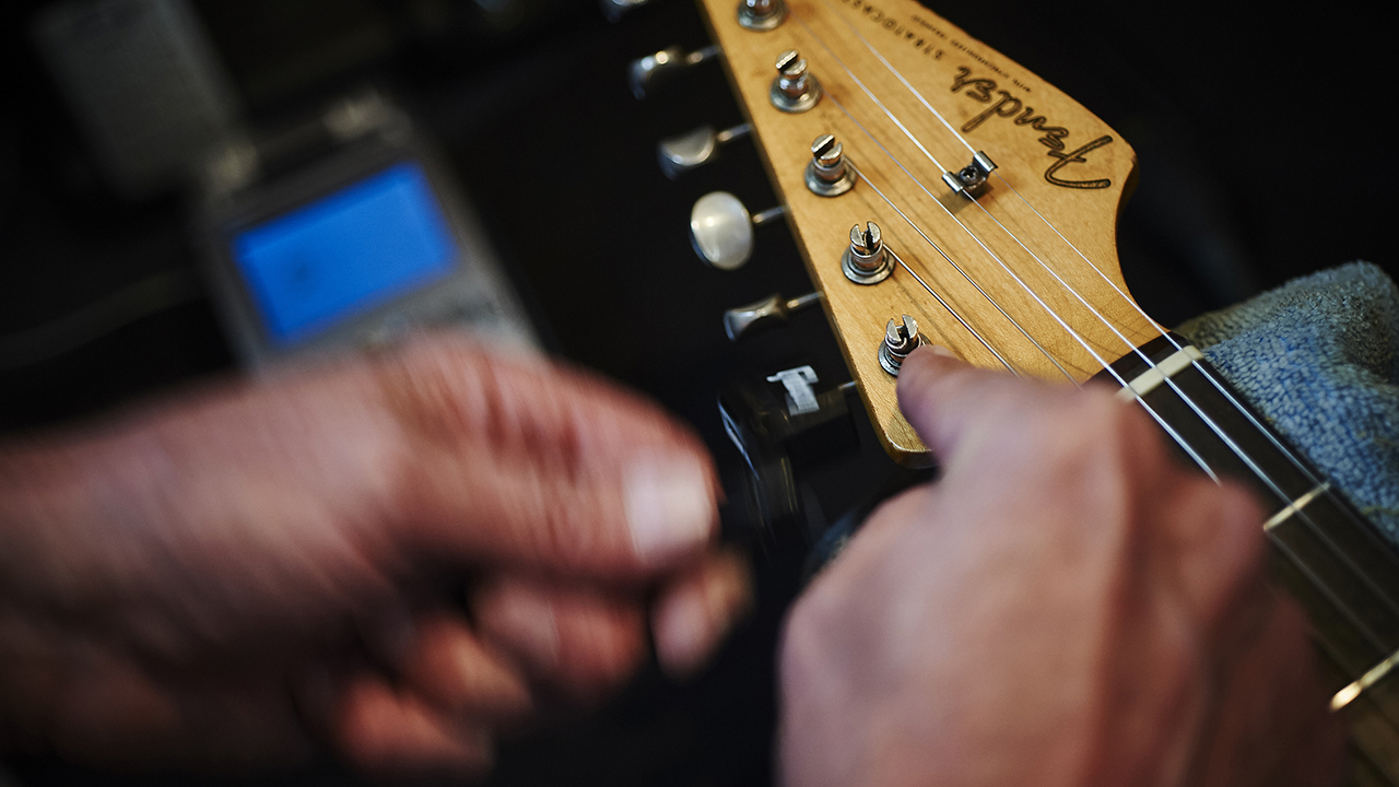 Closeup of hands changing guitar strings on a Fender Stratocaster
