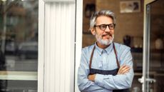 An attractive, happy entreprenuer stands in his shop doorway.
