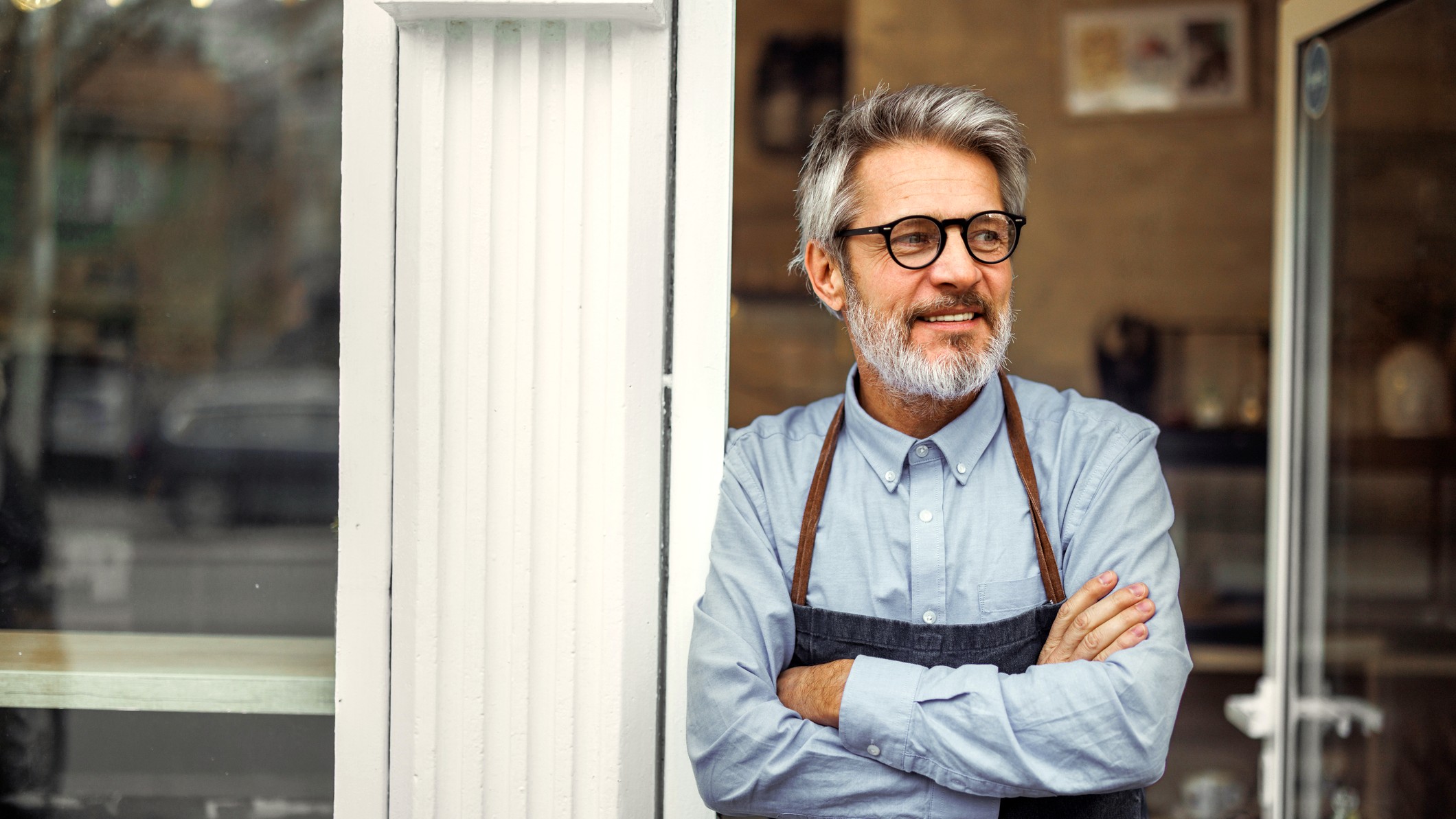 An attractive, happy entreprenuer stands in his shop doorway.