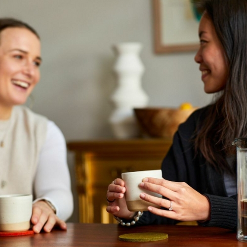 Image of a two women sitting at a table with coffee cups.