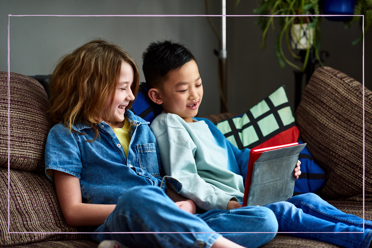 Two children studying together on sofa