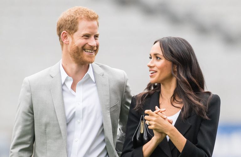Prince Harry smiling next to his wife Meghan, the Duchess of Sussex.