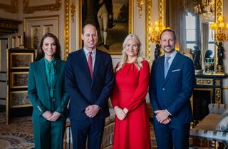 Kate Middleton wearing a green suit, Prince William wearing a blue suit, Crown Princess Mette-Marit in a red dress and Crown Prince Haakon in a blue suit posing together in a gilded room