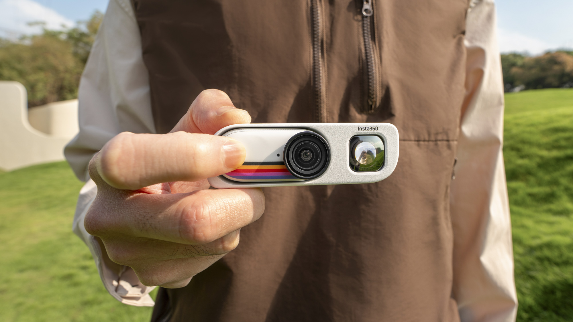 Insta360 Go 3S Retro edition, with the thumb-szied action camera slotted into the Retro Bundle's viewfinder case, held by a user