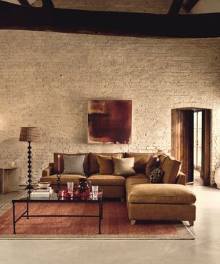checklist for modern rustic style, living room with caramel couch, russet rug, artwork, black metal and glass coffee table, plain and print couch pillows, painted brick wall, beams