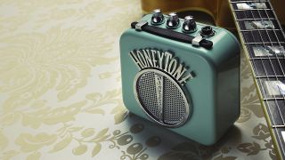 A Danelectro Honeytone mini guitar amp with an electric guitar lying next to it