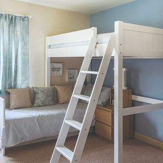 A bedroom with an elevated be and a sofa with a bedside table underneath it