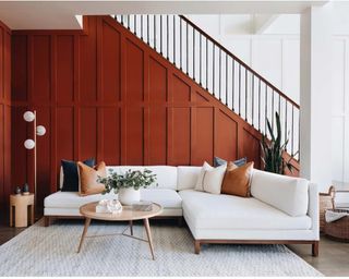 A white sectional sofa in a wooden panelled living room