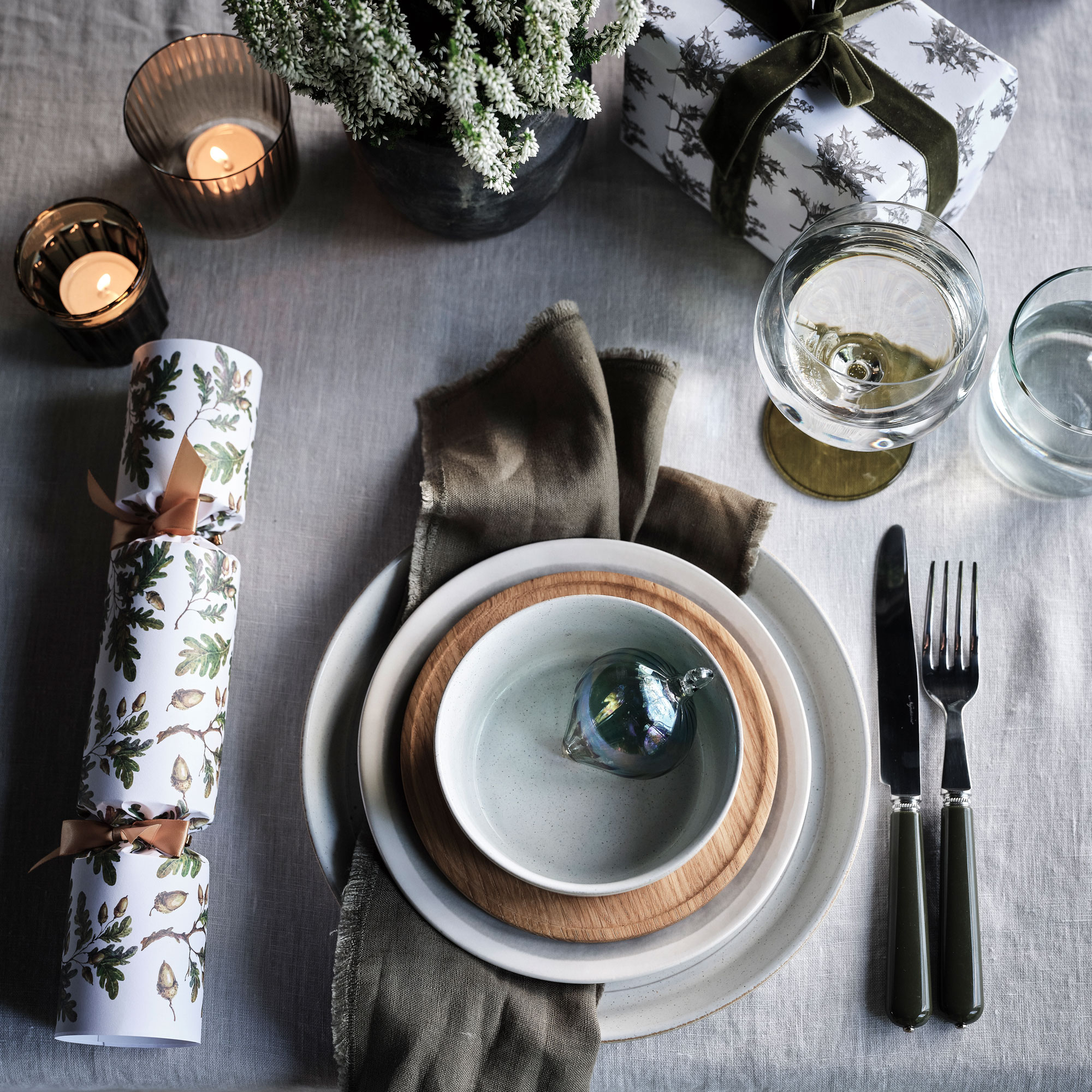 Grey table linen with white bowl, white plate, crackers and tea lights