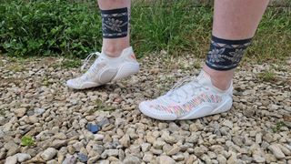 Vivobarefoot Motus Flex modeled by fitness writer Lou Mudge on a gravel path with grass in background.