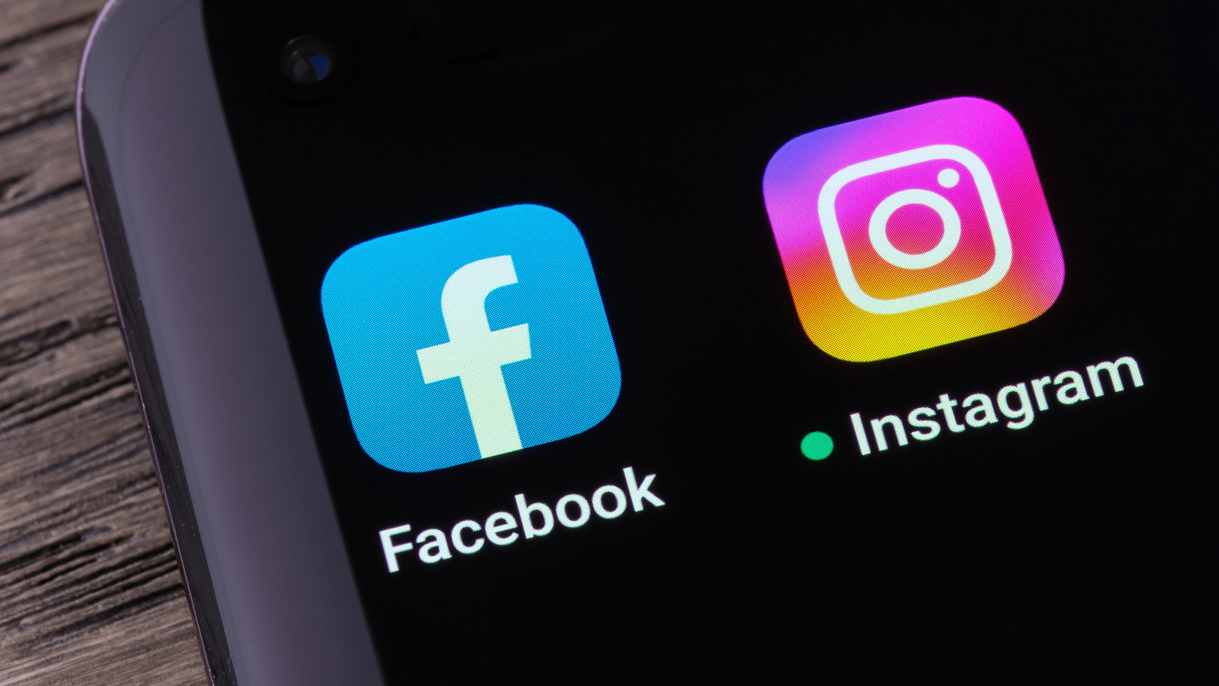 A phone on a table showing the Facebook and Instagram logos