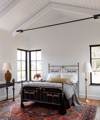 bedroom with cast iron bed and high ceilings with white walls